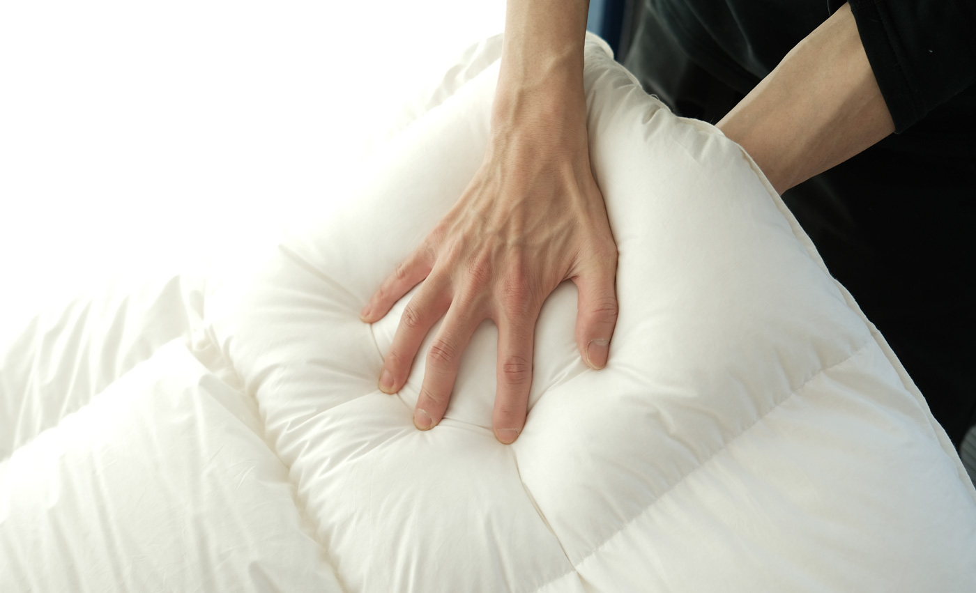 羽毛布団の反発を確かめる